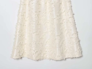 Detailed close-up of cream white midi skirt featuring high-end 3D jacquard fringe fabric