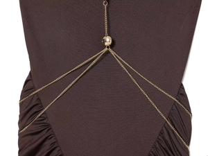 Dettaglio dell'elegante scollatura a catena dorata con un inserto a sfera in metallo