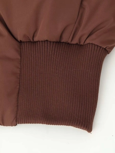 Close-up of ribbed cuffs and glossy fabric on dark brown winter hooded jacket