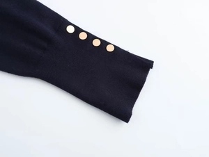 Close-up of navy blue knit sweater cuffs featuring ribbed texture and gold metal buttons