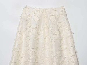 Detailed view of cream-white jacquard fabric with elegant 3D fringed texture and feathers