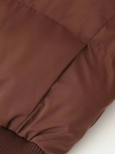 Detail of dark brown puffer jacket showing quilted fabric texture and ribbed hem