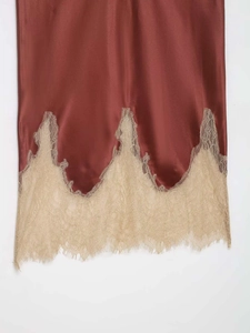 Détail de l'ourlet de jupe en satin rouille avec bordure en dentelle de cils beige