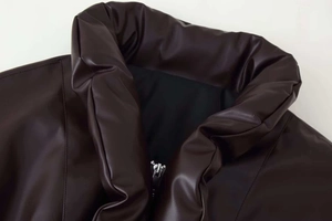 Detail shot of a dark brown faux leather winter jacket featuring a high collar and metal zipper