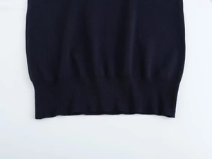 Detailed close-up of navy blue knit sweater featuring a ribbed hem and fine stitch texture