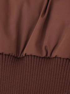 Detailed close-up of chocolate brown winter coat featuring ribbed knit hem and windproof fabric
