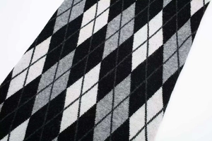 Primer plano detallado del patrón retro de rombos en punto negro, gris y blanco