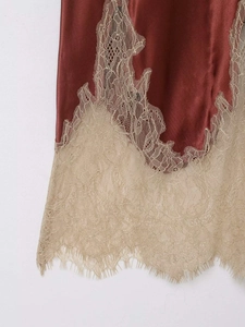 Détail d'une jupe en satin brun rouille avec ourlet en dentelle florale couleur champagne