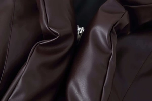 Macro detail showing the soft texture and stitching of dark brown faux leather jacket fabric