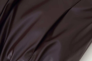 Macro texture of deep brown faux leather fabric showing fine grain and stitching details