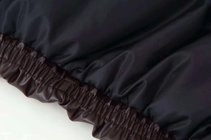 Detailed shot of dark brown PU leather jacket with elastic shirred hem and black lining