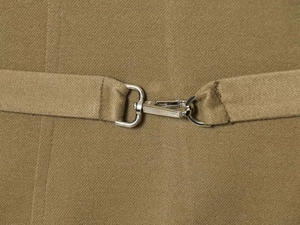Close-up of khaki twill fabric and silver metal lobster buckle on the adjustable waist belt