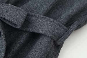 Dettaglio della trama del cappotto in misto lana grigio e della cintura annodata in vita