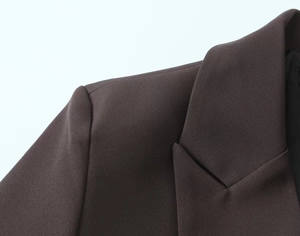 Detail of dark brown blazer showing sharp shoulder pads and tailored notch lapel texture