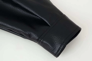 Close-up of litchi grain black leather texture and double-stitched cuff on the jacket