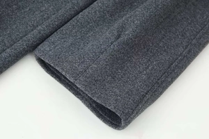 Dettaglio del polsino di un cappotto di lana grigio scuro con trama del tessuto e cuciture