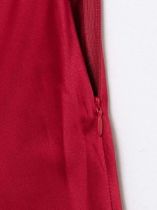 Detailed macro shot of a concealed zipper on a red satin halter neck dress