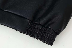 Detailed macro shot of the black leather texture and elastic ribbed cuff on the jacket