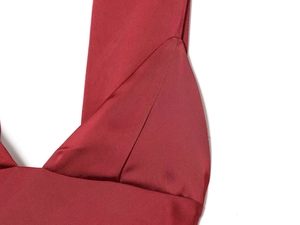 Détail d'une élégante robe en satin rouge foncé montrant le décolleté en V et la couture