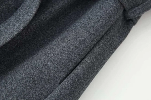 Dettaglio del tessuto di lana grigio scuro di un elegante cappotto invernale con trama pregiata