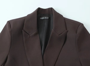 Detail view of the brown oversized blazer collar with a black brand label and inner lining