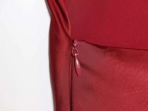 Détail de la fermeture éclair invisible sur une élégante robe longue en satin bordeaux