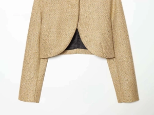 Detailed macro view of gold tweed cropped jacket with sequin texture and black lining