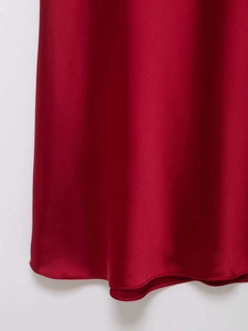 Detail of the dark red satin dress hem showing high gloss texture and fine stitching