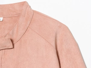 Detail view of pink faux suede jacket showing mock neck design and raglan sleeve seams