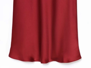 Détail du tissu satiné rouge vin avec un drapé élégant et une finition brillante soyeuse