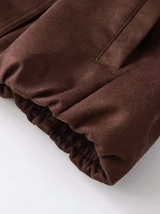 Detailed macro view of dark brown faux suede fabric jacket with pocket and hem stitching