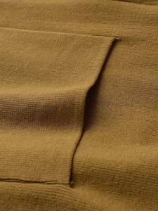 Gros plan sur la texture du tricot marron et les détails de couture de ce cardigan