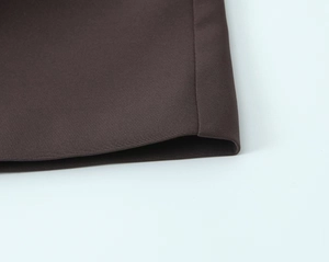 Detailed view of the dark brown fabric texture and hem fold craftsmanship of the blazer