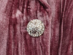 Close-up of textured silver metal button on mauve velvet fabric of the vintage set