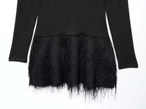 Detailed view of the delicate black fringe hemline on a slim-fit fashion dress