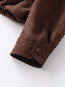 Detail view of dark brown faux suede jacket featuring sleeve cuff button and elastic hem