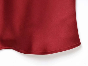 Gros plan de l'ourlet en satin rouge foncé avec texture lisse et couture soignée