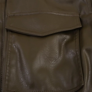 Detailed view of deep brown faux leather jacket featuring a sharp pointed flap pocket