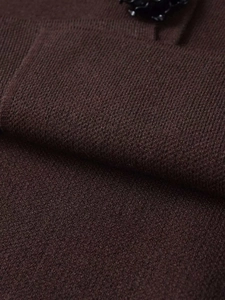 Macro shot of dark brown knit fabric with a stylish black jewel button detail
