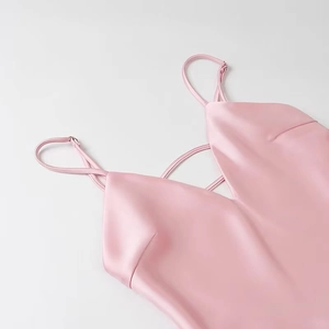 Detailed close-up of pink satin midi dress featuring a deep V-neck and criss-cross straps