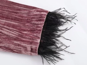 Detail of pink velvet sleeve with luxurious black feather trim and pleated texture