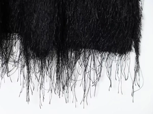 Close-up of high-quality black tassel fringe detailing on stylish slim-fit autumn dress