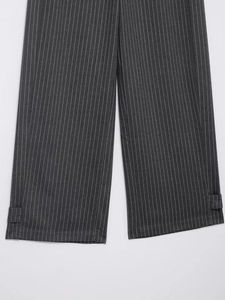 Detail einer dunkelgrauen Nadelstreifenhose mit dekorativen Knöchelriemen und edlem Stoff