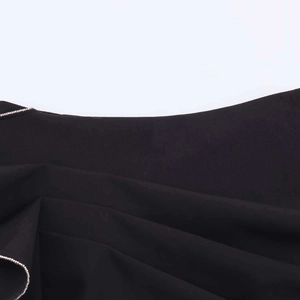 Makro-Detail des schwarzen Faltenstoffs mit elegantem silbernem Perlenketten-Besatz