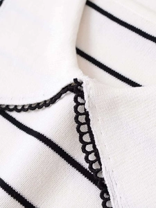 Detailed close-up of white and black striped knit top with delicate lace edges