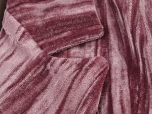Macro detail of dusty pink velvet suit lapel with vertical pleated texture and silky gloss