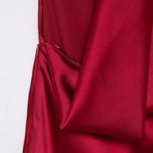 Detailed view of deep red satin dress fabric featuring a seamless invisible zipper closure