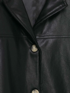 Detail of black faux leather jacket with notch lapel and amber-toned buttons