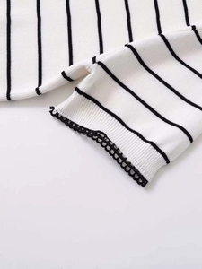 Macro shot of striped knit fabric with black lace trim detail on the sleeve edge