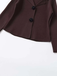 Close-up of brown knit cardigan featuring detailed black floral-shaped buttons
